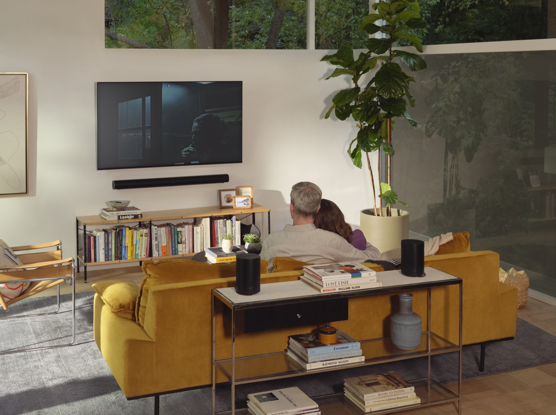 Couple enjoying a simple home entertainment system with a television, soundbar, and wireless speakers